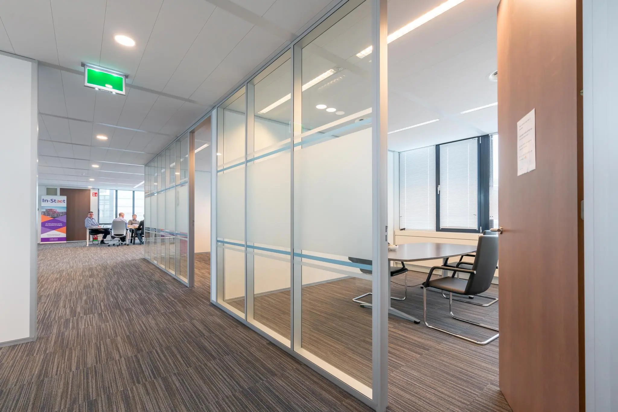 Moderne kantoorruimte aan de De Bruyn Kopsstraat met glazen vergaderruimtes en mensen in overleg.